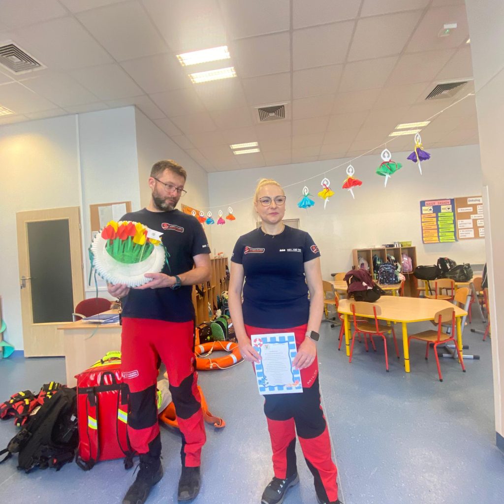 Ratownicy prezentują list gratulacyjny oraz kosz z kwiatami w dowód uznania od świetliczaków